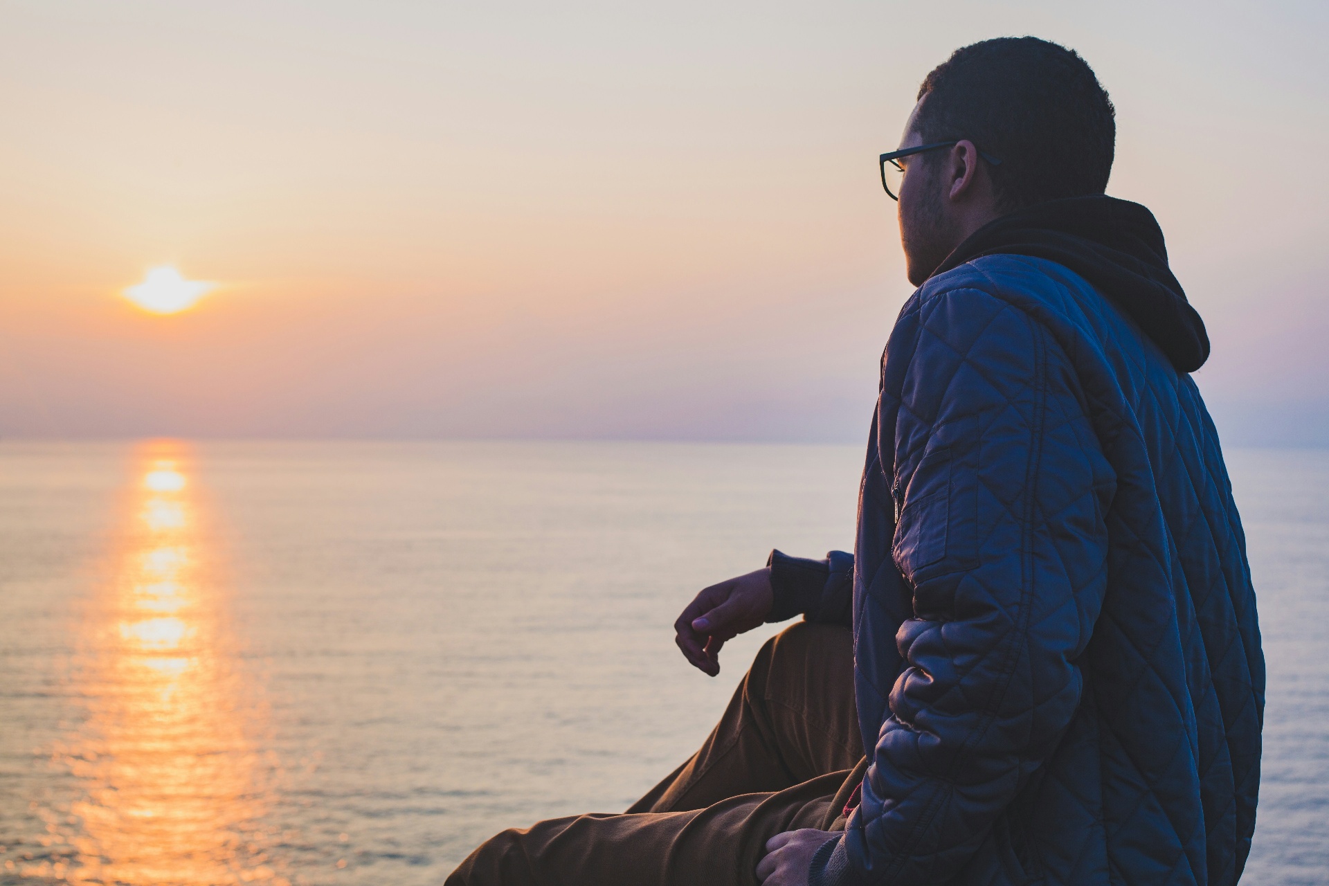 A man watching the sun set over the Pacific from the Huntington Beach coast