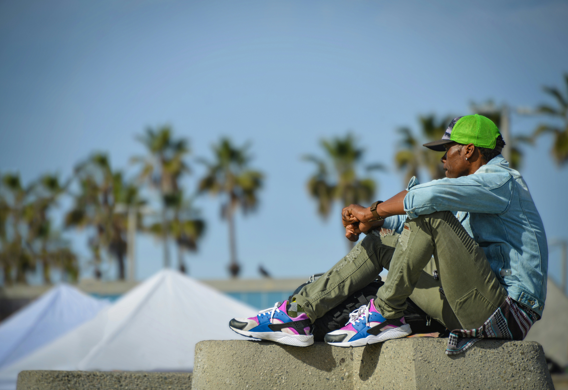 Person resting under palm trees along the Huntington Beach coast