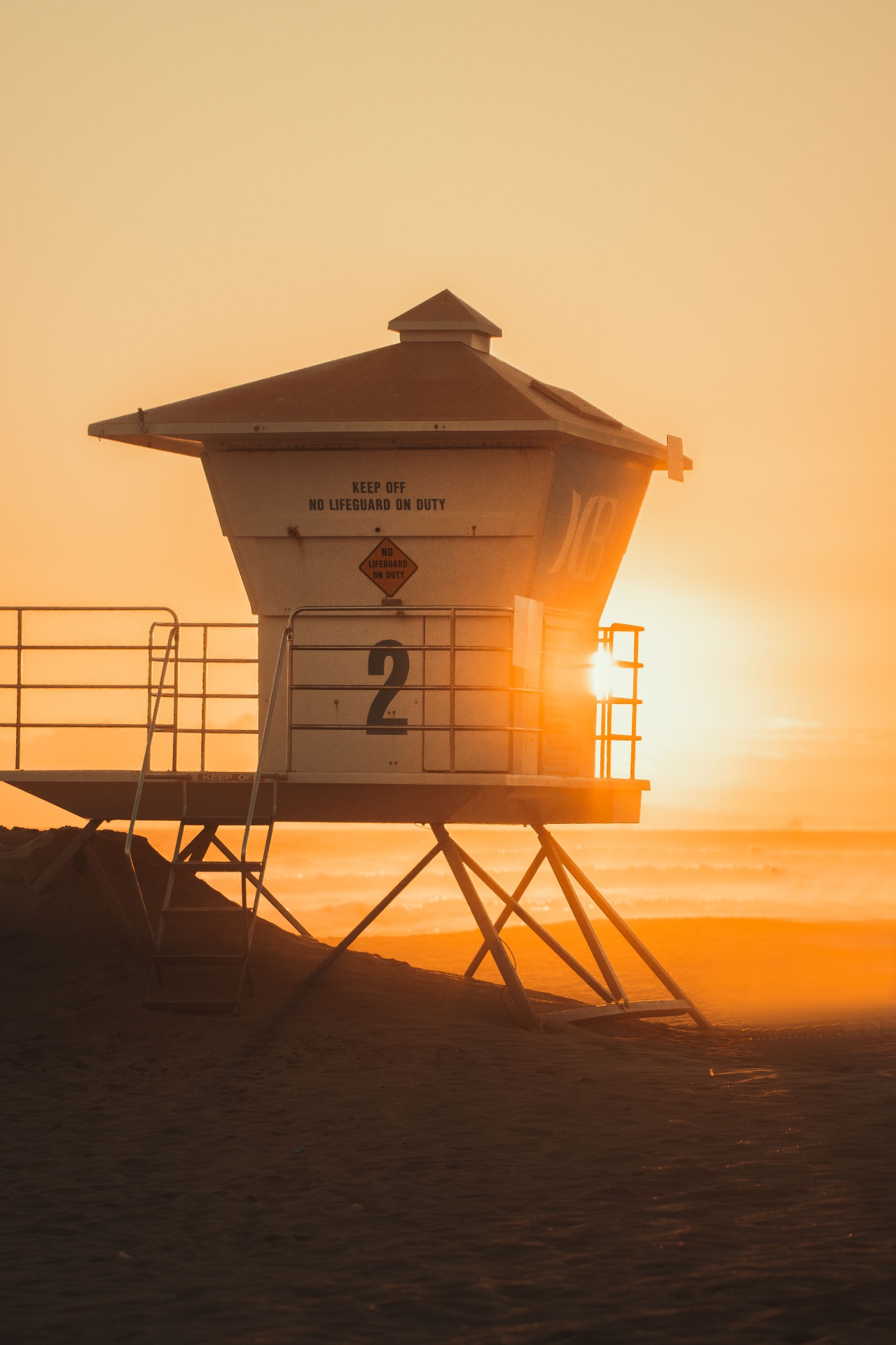 Huntington Beach lifeguard tower backlit by a warm sunset glow
